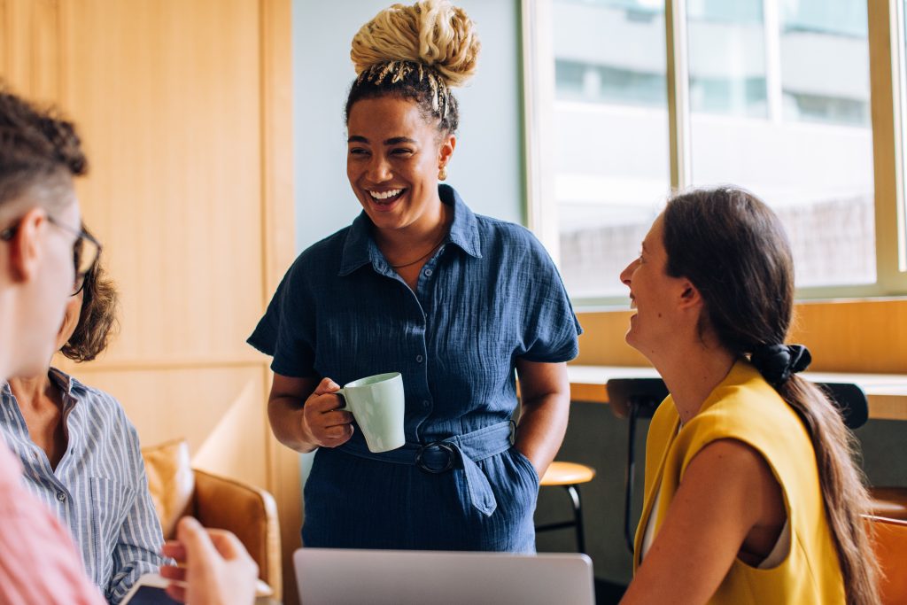 Des collègues souriants qui discutent dans un moment informel au travail.